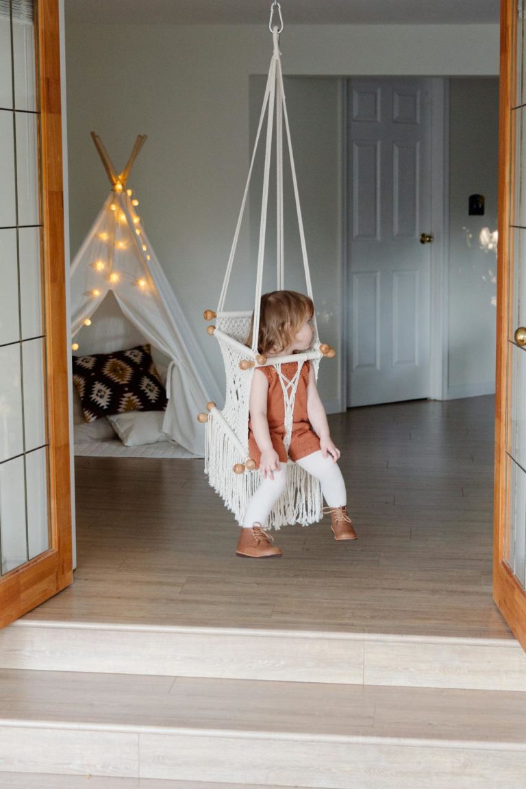 Little girl resting on swing in cozy room